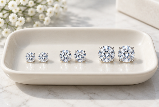 Moissanite stud earrings in increasing sizes on an ivory tray